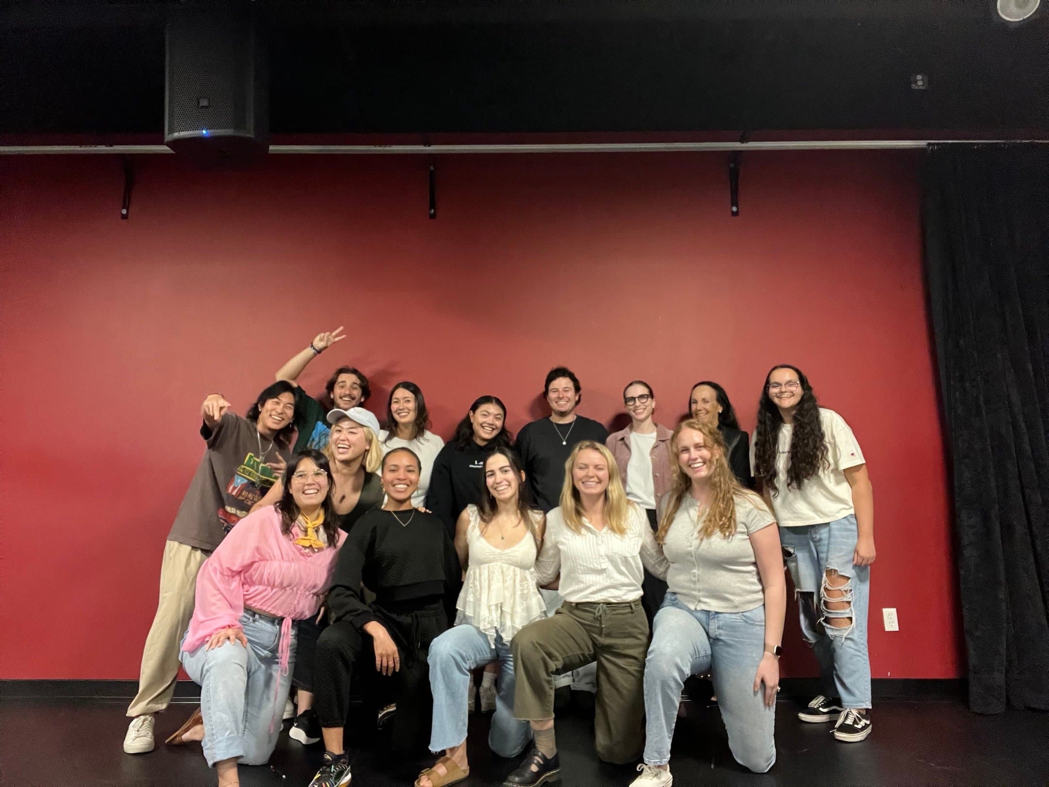 Photo of the cast in front of a red background.